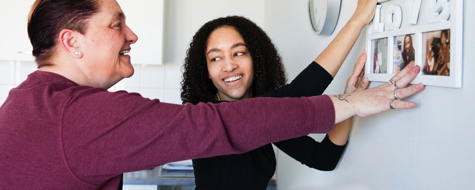Bewoner en begeleider hangen een schilderij op