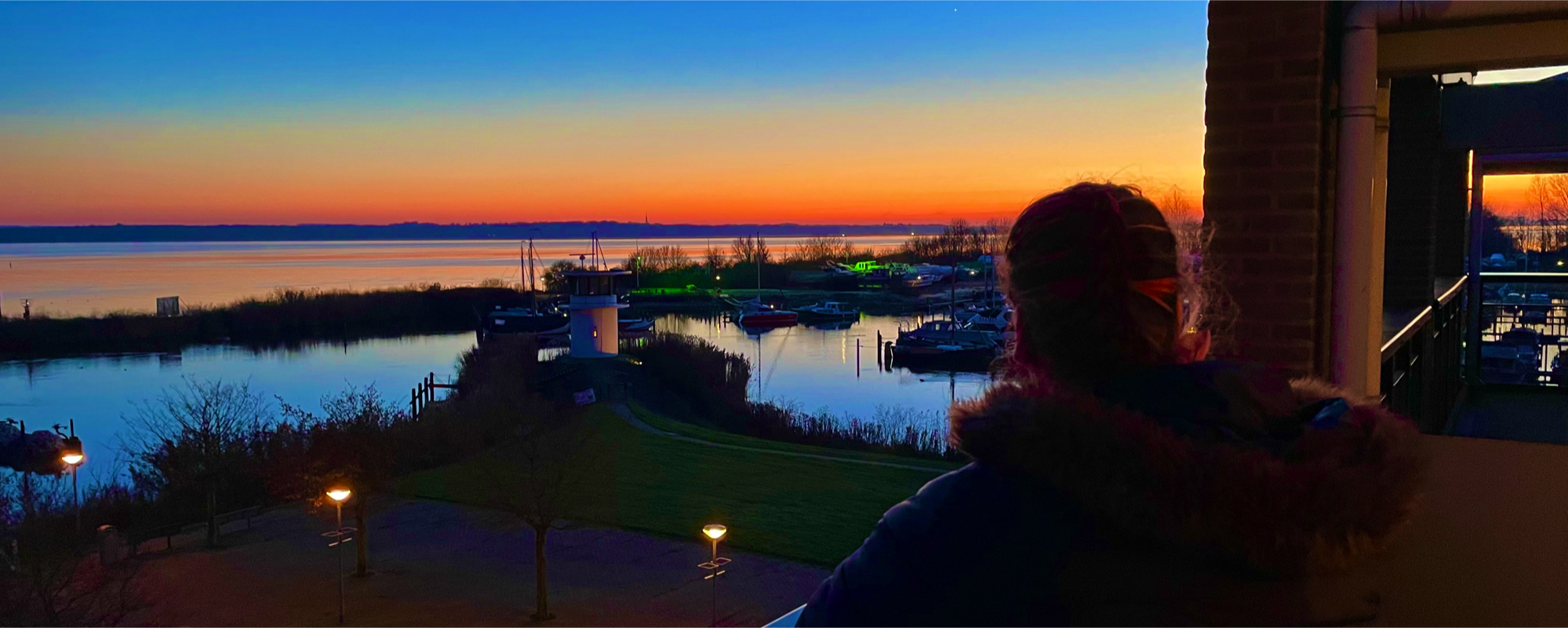 Dana kijkt naar de ondergaande zon vanaf haar balkon